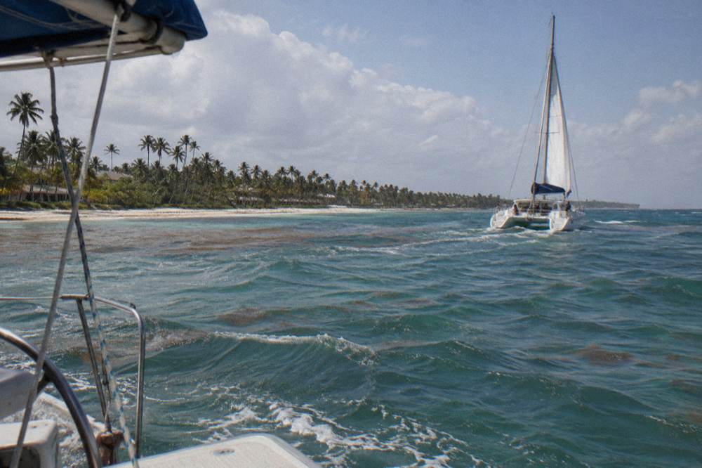 Catamaran sails along the Bavaro coastline under scattered afternoon clouds